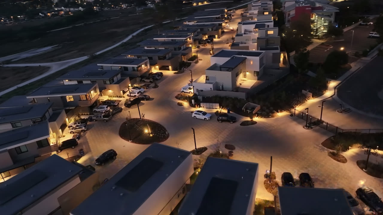 Aerial drone footage of a housing development at dusk wipes across into a Gaussian-splat reconstruction of the same street, which then dives to the roundabout and climbs back out to a wide view